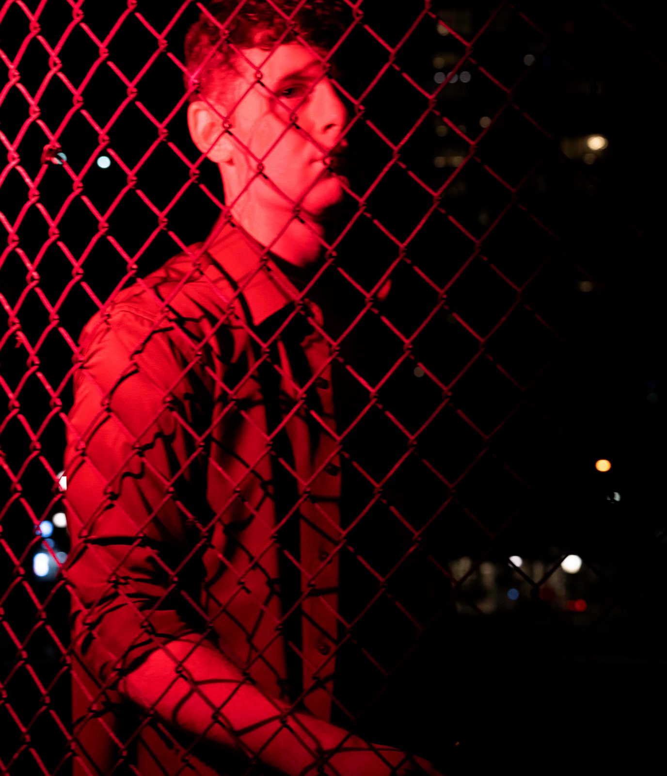 Sean Kennedy behind a red-lit chain-link fence